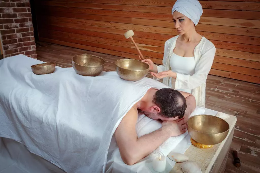 woman performs tibetan singing bowl 77025105 - Teknik Relaksasi Terbaru yang Dapat Mengurangi Stres: Apa Itu Sound Bath?